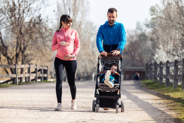 pareja joven deportiva con su pequeño hijo caminando mientras disfruta el tiempo juntos al aire libre. - relaxation exercise child mother human pregnancy fotografías e imágenes de stock