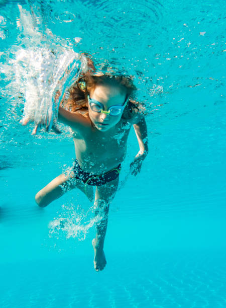 istock Little boy swimming underwater in pool 1218816552