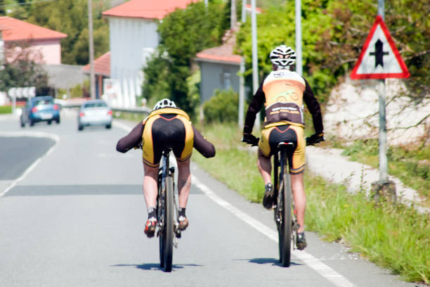 A Coruña, Spain- April 21, 2019: Rear view of two young male cyclists riding fast, wearing sports clothing, seen along a country road in A Coruña, Galicia, Spain.