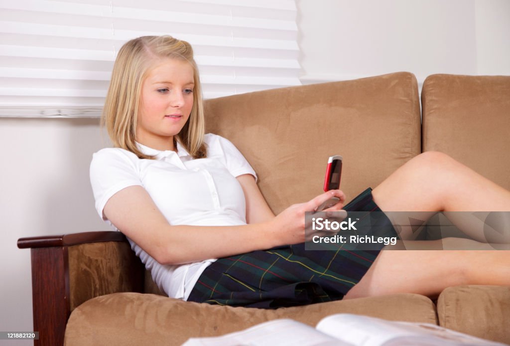 High School Student A smiling teenage girl texting on the phone while doing her homework. Beautiful People Stock Photo