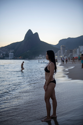 In Rio de Janeiro, a young American woman traveling in Brazil stands at Ipanema Beach, one of the world's most famous and scenic stretches of sand.