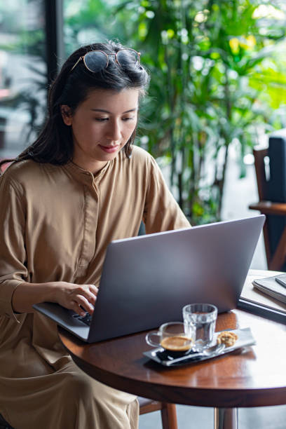 istock Freelancing at a Cafe: Young Asian Entrepreneur Working on Her Laptop Computer 1218822025