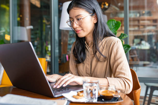 istock Online Business: Asian Blogger Writing on Her Laptop Computer in a Coffee Shop 1218822059