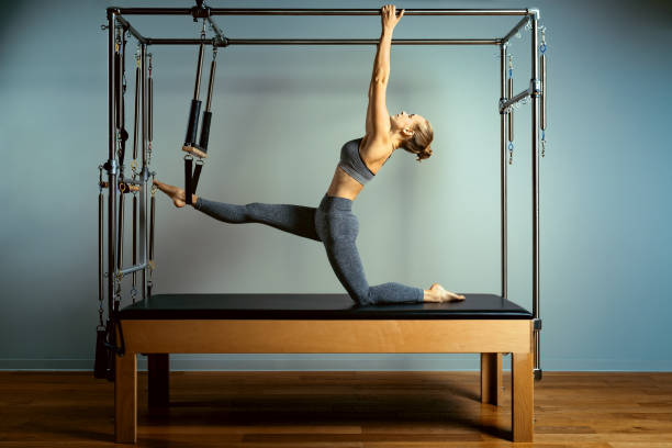 Active motivated woman does exercises in bed reformer, beauty and health. Plastic, posture, smart fitness stock photo