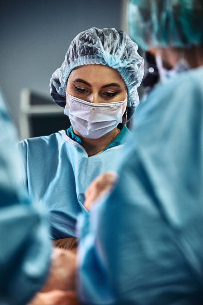 병원 수술실에서. 전문 외과 의사와 조수의 국제 팀은 현대적인 수술실에서 작동합니다. 전문 의사는 성공적으로 생명을 구한 축하 - 진료소 이미지 뉴스 사진 이미지