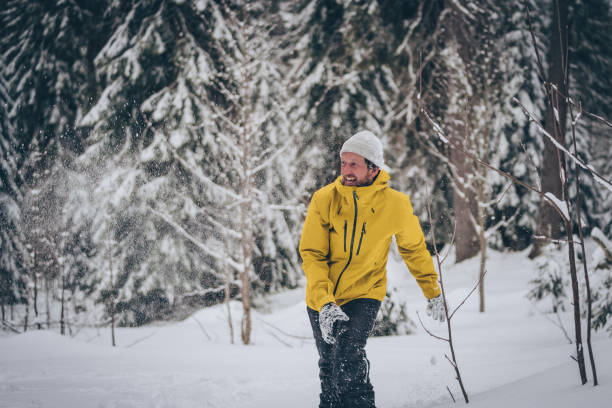 istock Man in snowy forest throws snowball into the air 1218824619