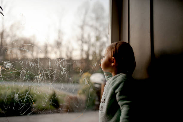 Toddler Looking Out Through Scribbled On Glass Door Toddler during coronavirus pandemic stuck indoors and looking out looking out front door stock pictures, royalty-free photos & images