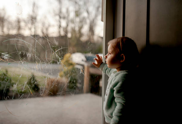 Toddler Looking Out Through Scribbled On Glass Door Toddler during coronavirus pandemic stuck indoors and looking out looking out front door stock pictures, royalty-free photos & images