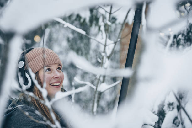 mujer joven con equipos de sonido caminatas a través del bosque nevado - fresh snow audio fotografías e imágenes de stock