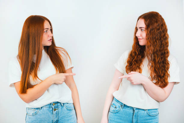 istock two redheaded young women both pointing with finger one at another standing on isolated white backgroung, body language concept 1218827779