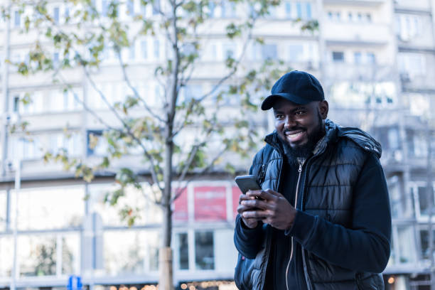 istock Fit young black man walking outdoors with mobile phone 1218830563
