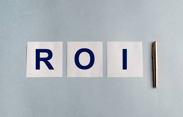 istock ROI (Return On Investment) acronym on white stickers and golden pen on grey blue background 1218831375