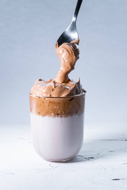 istock orean dalgona coffee and spoon with cream coffee falling into a glass on white background. Vertical picture. 1218831941