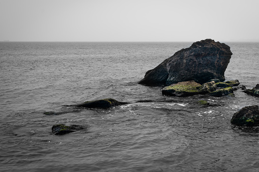 Seascape rock in the water, natural background of marine nature, waves wash the large stones from the shell. Calm sea.