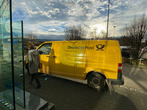 german woman walking near the yellow volkswagen deutsche post dhl van - deutsche post ag package germany occupation imagens e fotografias de stock