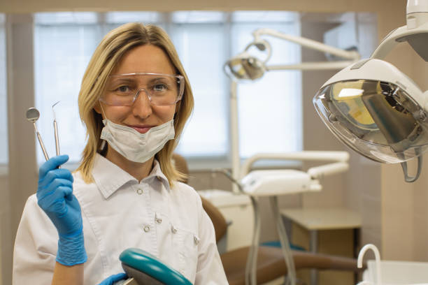 istock Dentist woman with tools over medical office background. 1218834939
