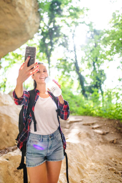 istock Woman drinking water, taking a selfie and walking on mountain 1218836897