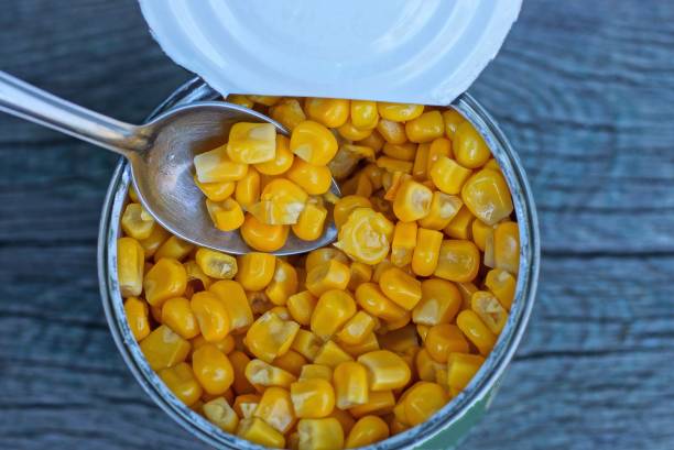 istock open tin can with yellow tinned corn and a small metal spoon 1218839082