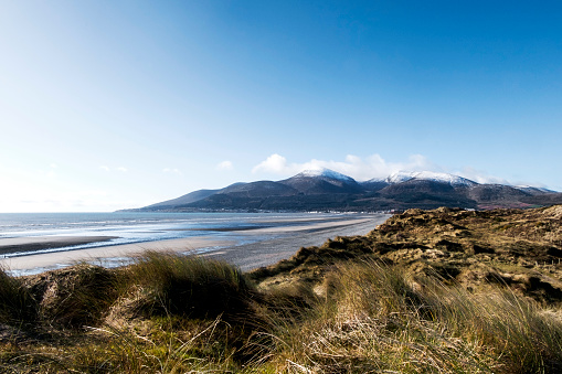 The Mourne Mountains, County Down, Northern Ireland. The photograph is taken from Murlough Bay looking towards the town of Newcastle in Northern Ireland. The photograph consists of Mountains, the sea, the beach and sand dunes.