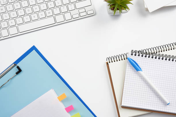 istock White wireless keyboard, a stack of notebooks, green plants in pots and a mouse, workplace of a freelancer 1218842657