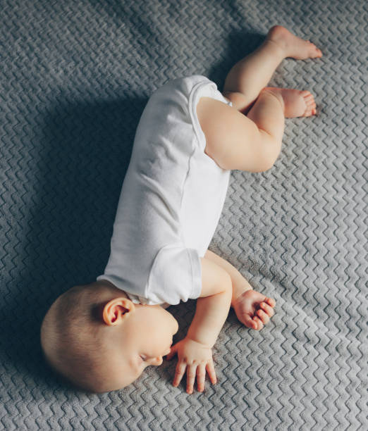 istock Sleeping baby boy in white bodysuit in bed 1218847080