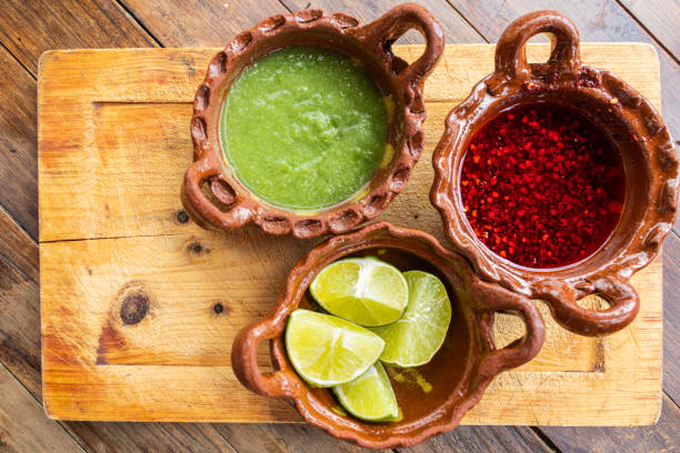 nourriture mexicaine : salsa picante verde, sauce chili épicée aux arbres et citrons dans des pots d’argile - arbol photos et images de collection