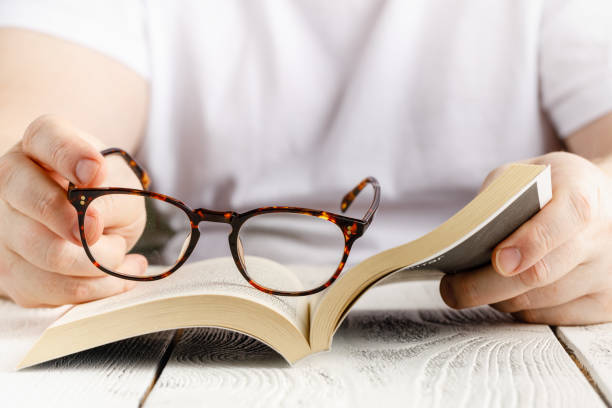 istock Reading book close up view in hands with glasses 1218849950