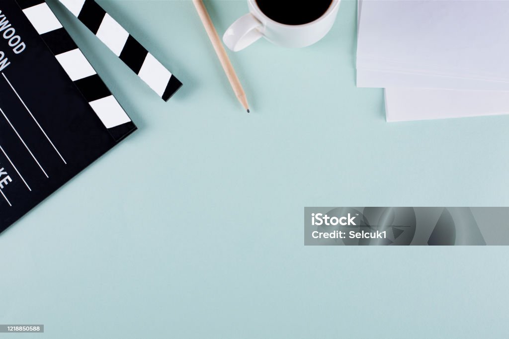 Movie clapper board and coffee cup on blue background with copy space Filmmaker equipment Put on a pastel blue background with copy space. Film Script Stock Photo