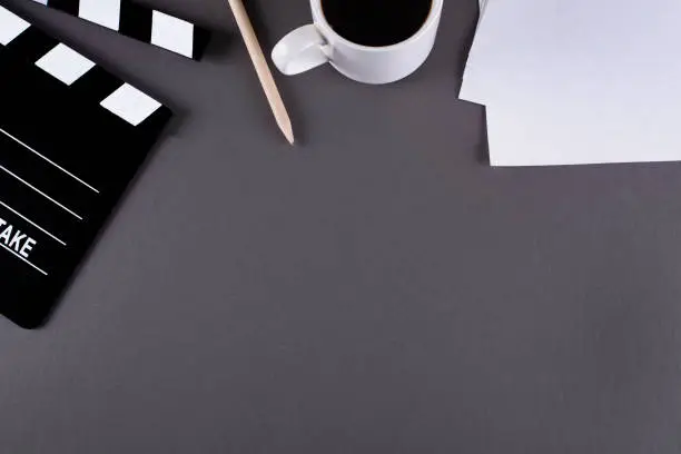 Photo of Movie clapper board and coffee cup on dark background with copy space