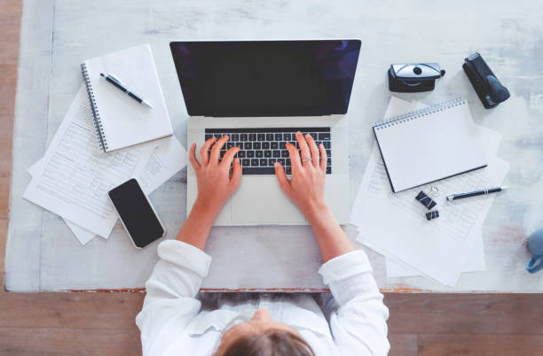 istock Top view of woman using laptop while sitting at the table with laptop, mobile phone, note pad, 1218851373