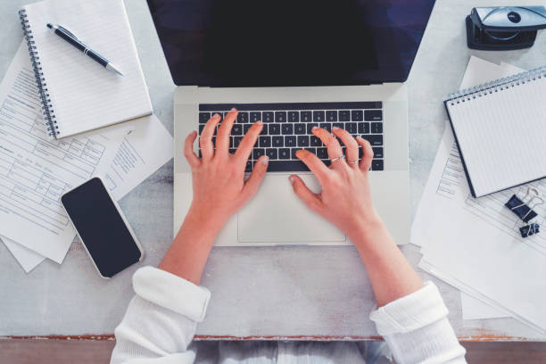 istock Top view of woman using laptop while sitting at the table with laptop, mobile phone, note pad, 1218851376