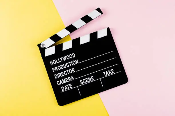 Photo of Movie clapper board on yellow and pink background with copy space.