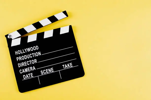 Movie clapper board on yellow background with copy space.