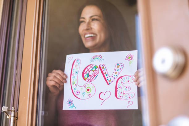 hermosa pre senior madura adulto femenino sosteniendo registro en ventana - women sign love trap fotografías e imágenes de stock