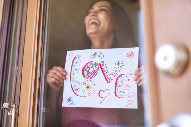 hermosa pre senior madura adulto femenino sosteniendo registro en ventana - women sign love trap fotografías e imágenes de stock