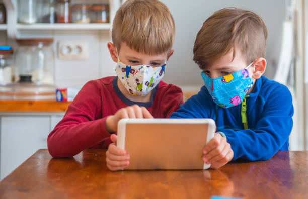 istock Boys Playing With Digital Tablet And Wearing Protective Face Mask 1218853837