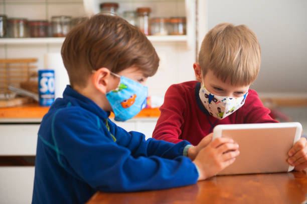 istock Boys Playing With Digital Tablet And Wearing Protective Face Mask 1218853990