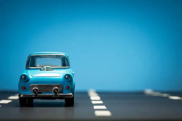 Photo of Blue toy car on an asphalt road.