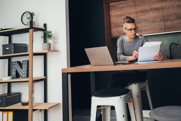 istock Business woman reading reports at home 1218860617