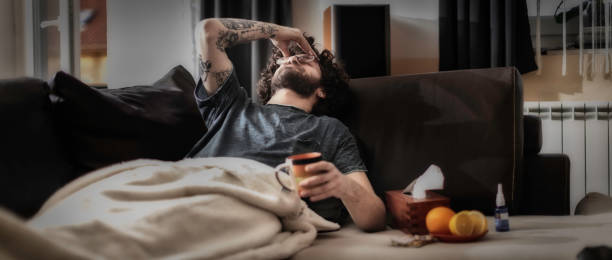It's the season of sneezes Young man suffering from headache, migraine or hangover at home drunk photos stock pictures, royalty-free photos & images