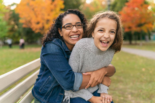 istock Playful mother and daughter laughing on park bench 1218865407