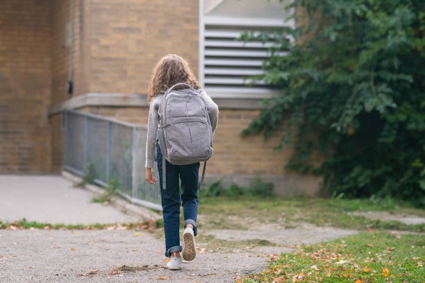 istock Elementary age girl walking in to school 1218865414