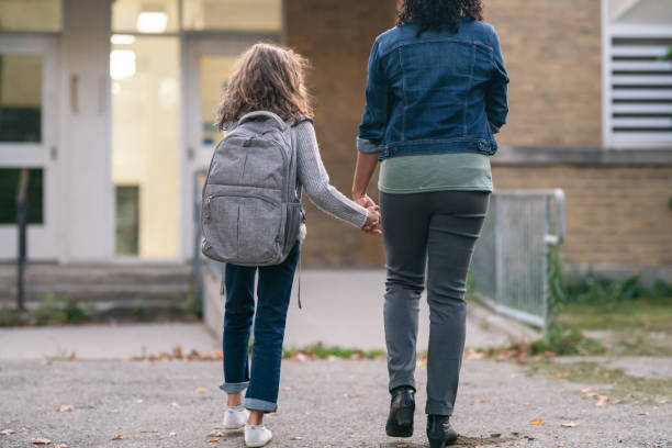 istock Mom holds daughter's hand while walking to school 1218865423