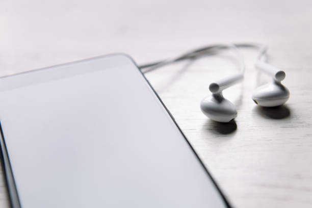 smart phone with earphones on white wooden table, music and podcast concept, copy space for text