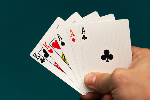 set of five different play cards in a hand on a green background