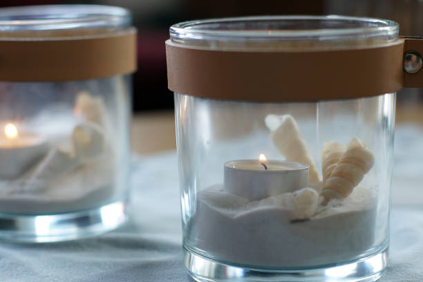 istock Two candles in transparent candlesticks with sand and a shell are on the table 1218871880