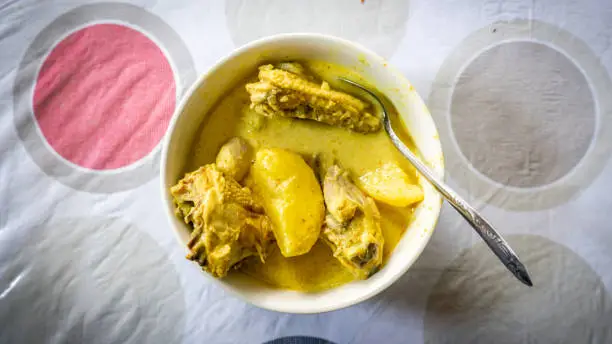 Photo of Ayam Masak Lemak Cili Api/ Chicken stew in coconut milk- traditional Malay cuisine in white bowl on table. Add with potatoes and turmeric. Homemade dish. Common food for lunch. Spicy and creamy taste.