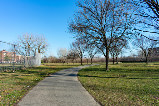 An empty curving walkway at a grass field at Kissena Park in Flushing Queens New York