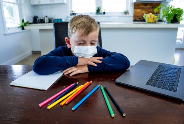 istock COVID-19 pandemic isolation and online education learning. School boy with face mask watching online classes feeling bored and depressed at home.  Coronavirus Outbreak. Lockdown and school closures. 1218876855