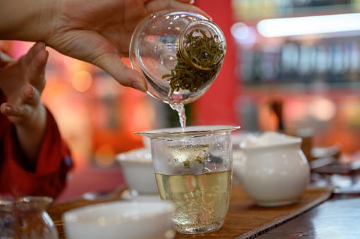 Close-up of woman pouring oolong tea into glass tea cup, Nikon Z7